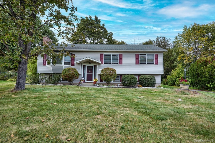 Bi-level home featuring a front yard and a chimney