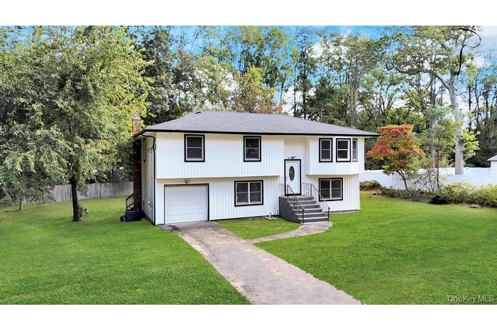 Bi-level home featuring a garage, driveway, and a shingled roof