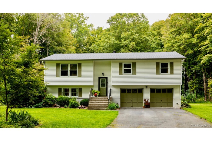 Raised ranch with driveway, a front yard, and a garage