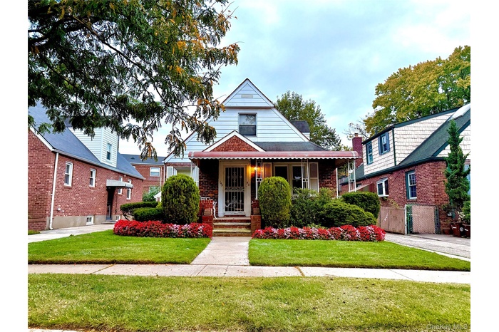View of front facade featuring a porch, brick siding, and a front lawn