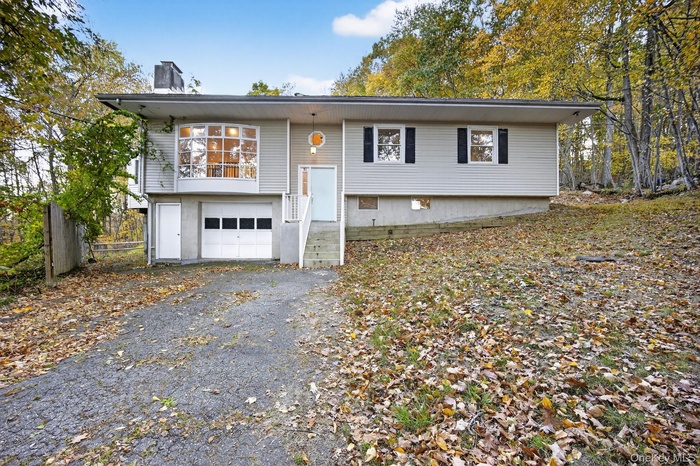 Raised ranch featuring a chimney, driveway, and a garage