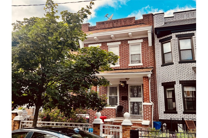 View of front facade with a fenced front yard, brick siding, and covered porch