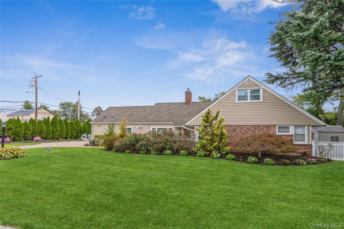 View of front of property featuring a front yard, brick siding, and a chimney