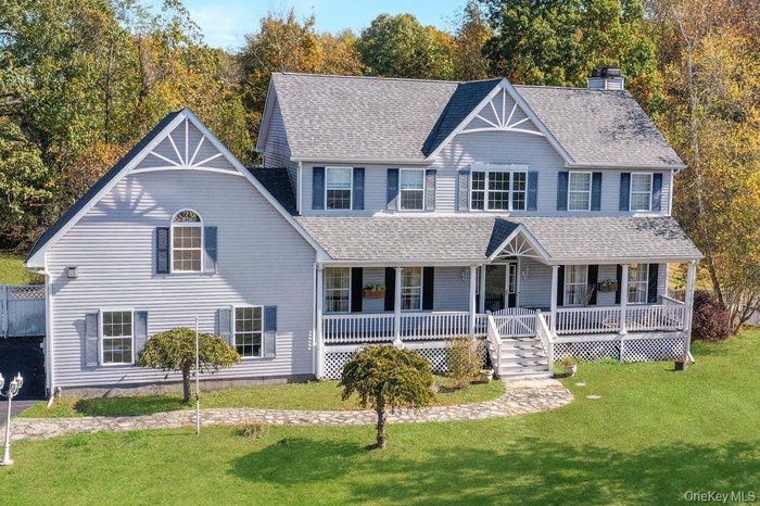 View of front of house featuring covered porch, a chimney, and a front lawn