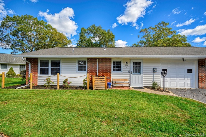 Single story home featuring a front lawn, a garage, brick siding, and driveway