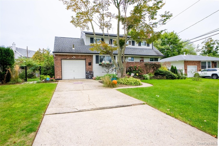 Traditional home featuring concrete driveway, a shingled roof, and brick siding