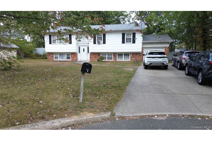 Bi-level home featuring a front yard, brick siding, and driveway