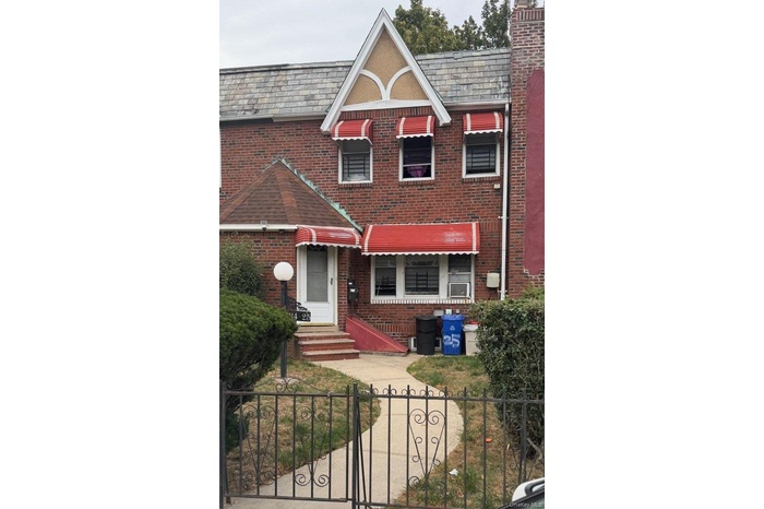 View of front facade with a high end roof, a fenced front yard, a gate, and brick siding