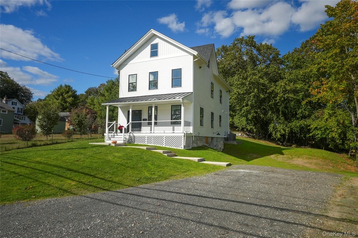 View of front of property featuring a standing seam roof, a porch, a metal roof, a front yard, and board and batten siding