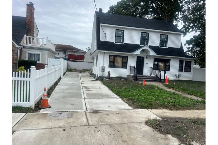View of front of home with roof with shingles, a chimney, and concrete driveway
