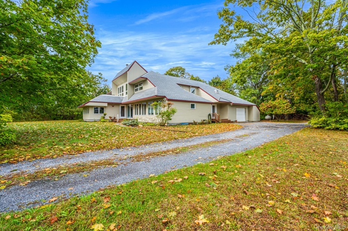 View of home's exterior with driveway, roof with shingles, an attached garage, and a lawn