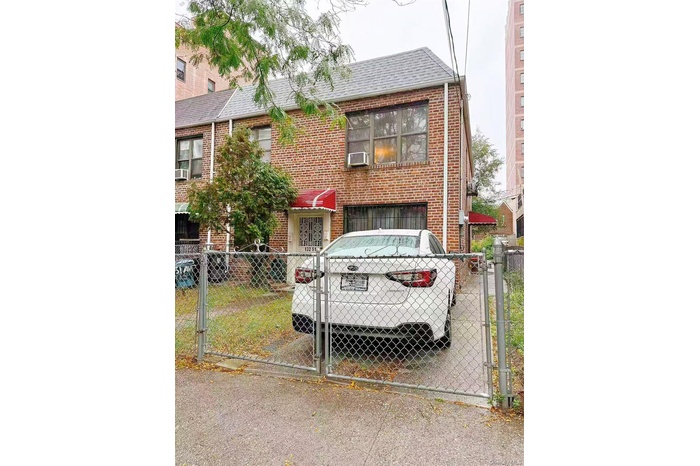 View of front facade with a gate, a fenced front yard, roof with shingles, and brick siding