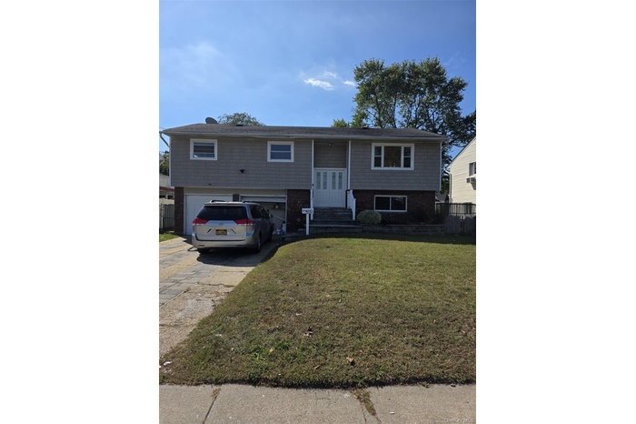 Bi-level home featuring brick siding, concrete driveway, and a garage