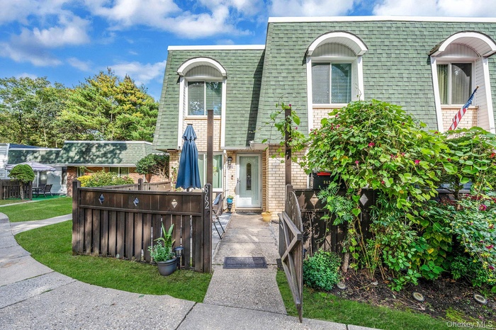 Property entrance with mansard roof, a shingled roof, and brick siding