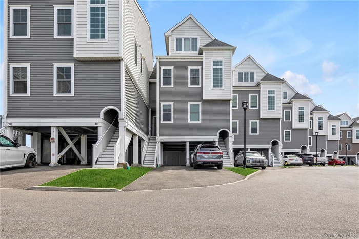 View of front of home with stairs, a residential view, asphalt driveway, and a carport