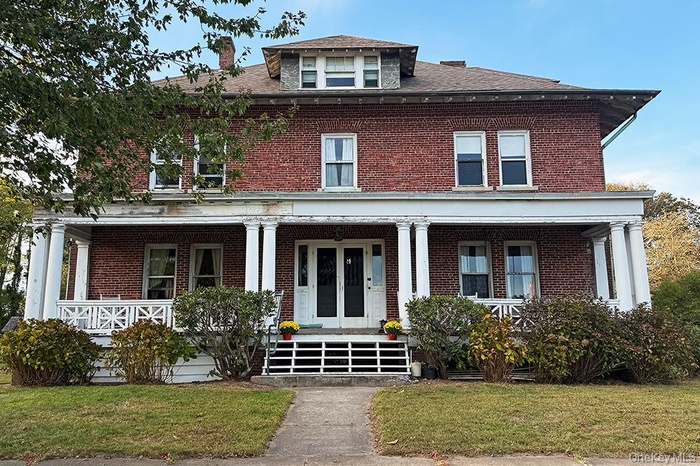 American foursquare style home with brick siding, a porch, and a front lawn