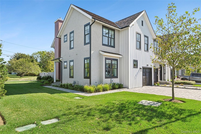 View of front of home featuring board and batten siding, a front lawn, decorative driveway, and a garage