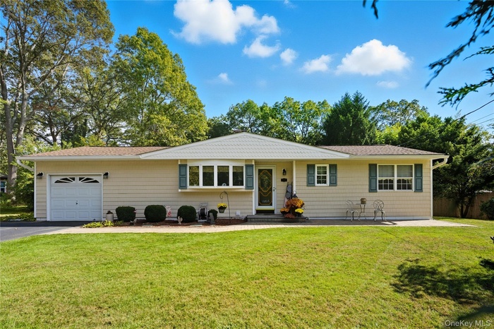 Single story home featuring a front yard, an attached garage, asphalt driveway, and a shingled roof