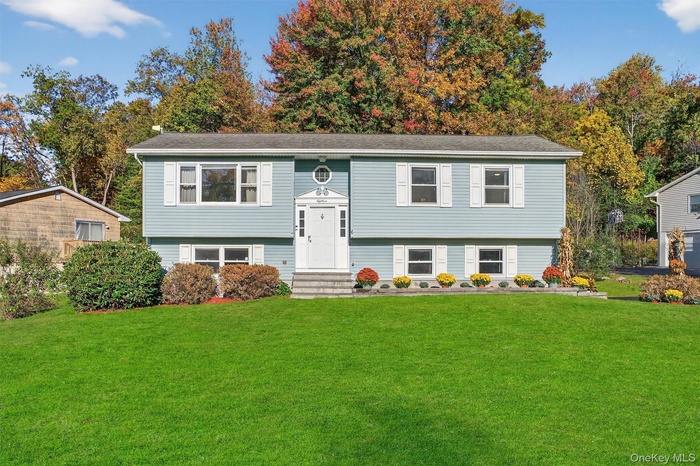 Split foyer home with a front yard and entry steps