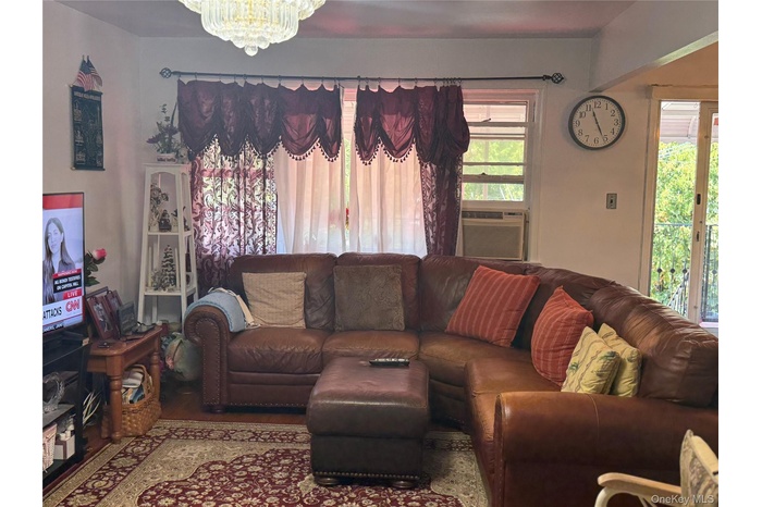 Living area with wood finished floors, a chandelier, and cooling unit
