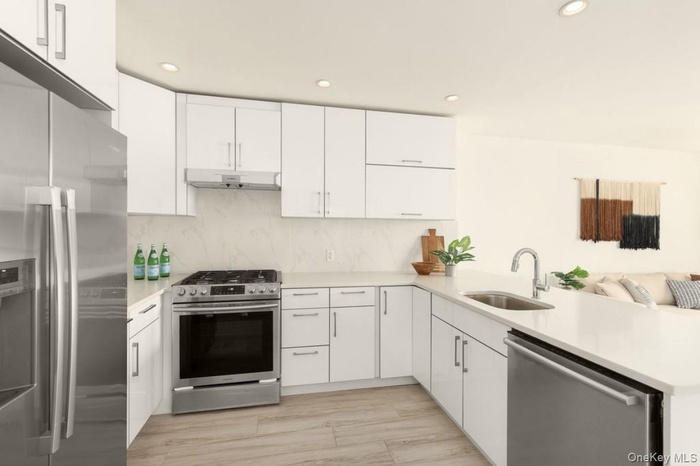 Kitchen featuring appliances with stainless steel finishes, white cabinetry, recessed lighting, light stone countertops, and tasteful backsplash