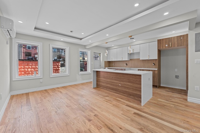 Kitchen with modern cabinets, brown cabinets, white cabinets, light stone countertops, and recessed lighting