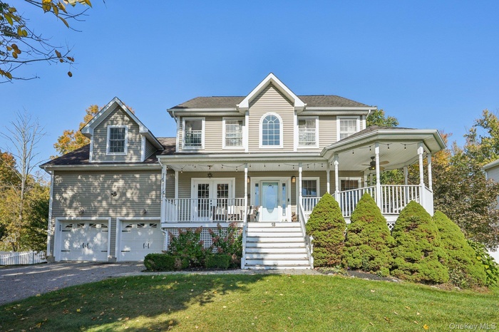 View of front of house with a porch, a front lawn, asphalt driveway, stairway, and a garage