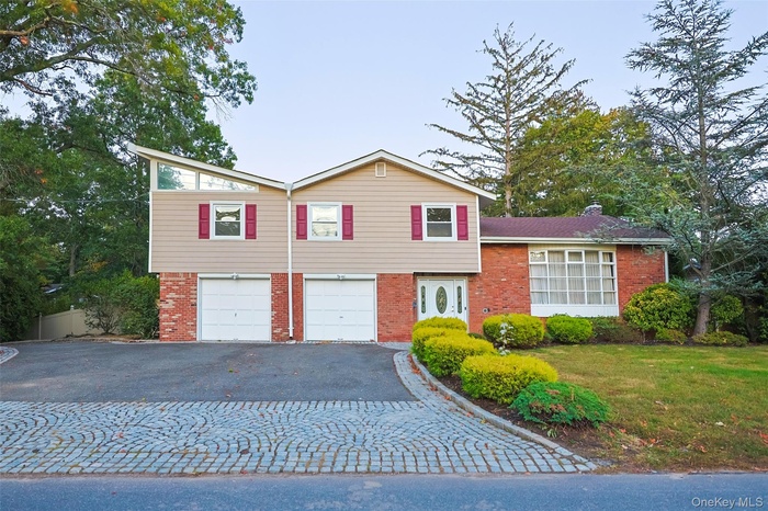 Front Exterior (Daytime View) – The home’s modern split-level design shines in natural daylight, featuring a mix of brick and siding, fresh landscapin