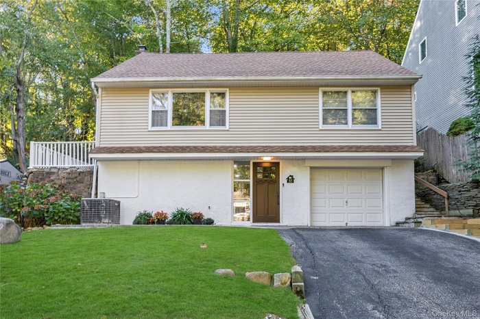 View of front of home featuring asphalt driveway, roof with shingles, stucco siding, and a garage