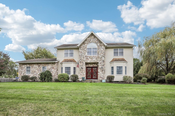 View of front of house with stone siding and large front lawn.