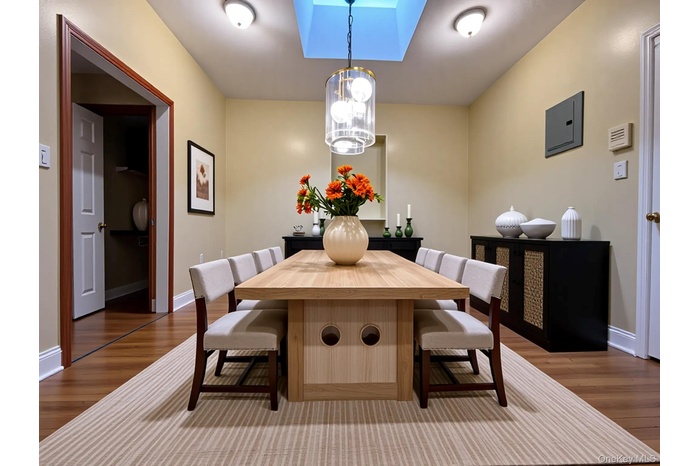 Dining room with a skylight, dark wood-type flooring, and a chandelier