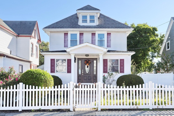 American foursquare style home with a shingled roof and a fenced front yard