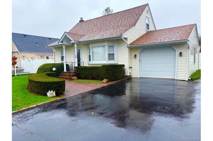 View of front facade featuring a garage, roof with shingles, and asphalt driveway