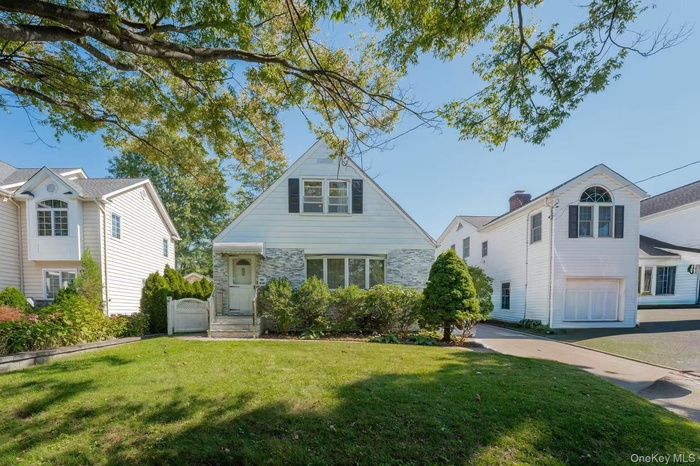 View of front facade with a front yard and stone siding