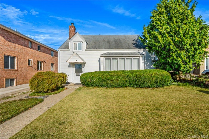 View of front of property featuring a front yard and a chimney