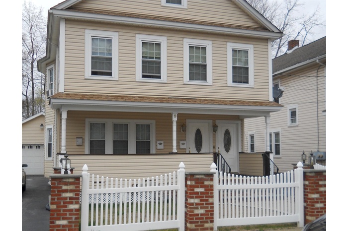 View of front of house with fence, covered porch, and a garage