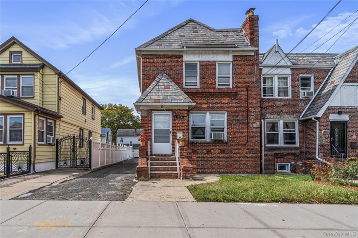 View of front of home featuring brick siding, a gate, and a chimney