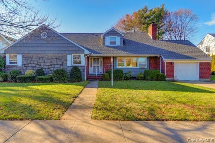 View of front of house featuring a front lawn, an attached garage, and a chimney