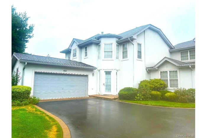 View of front facade with driveway, stucco siding, and a garage