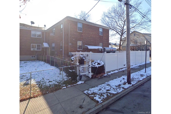 Snow covered house with a fenced front yard, brick siding, and a gate