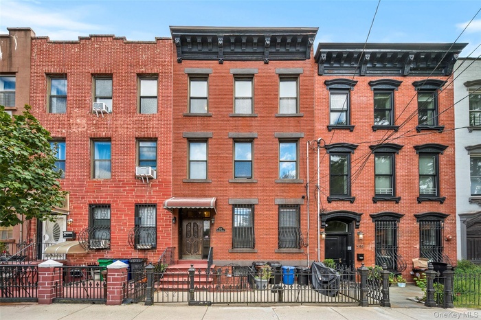 Italianate home featuring brick siding, a fenced front yard, and a gate