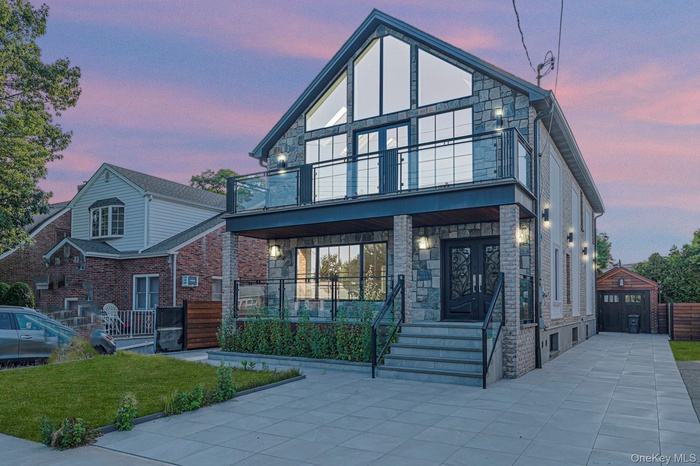 Modern home with stone siding, a balcony, and covered porch