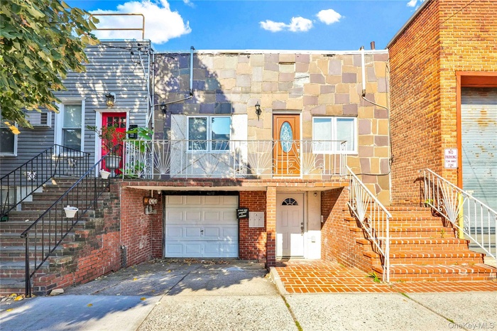View of front of home featuring a garage, stairs, driveway, and a balcony