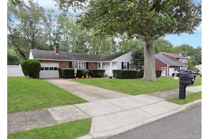Single story home featuring a chimney, a front lawn, and brick siding