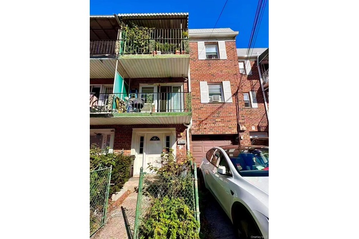View of front of property with brick siding, a balcony, and a gate
