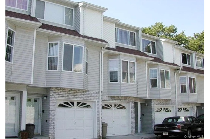 View of front of home featuring a garage, brick siding, and driveway