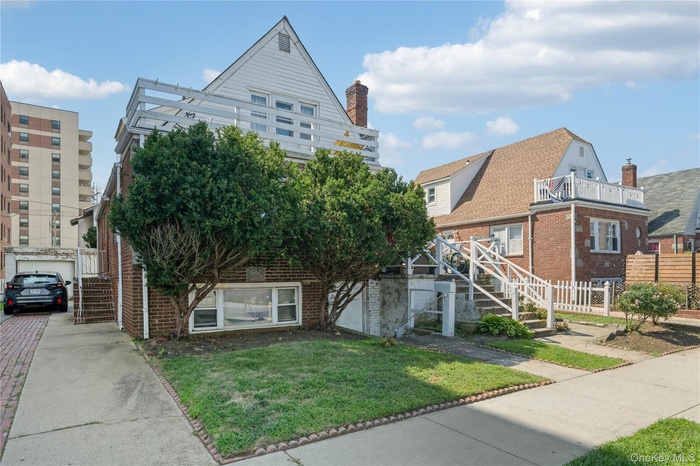 View of front of house with stairway, brick siding, and a balcony