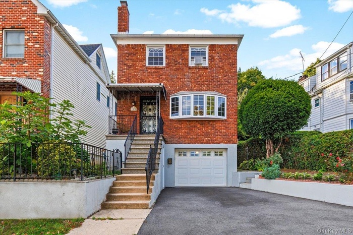 View of front facade with brick siding, a chimney, asphalt driveway, and a garage