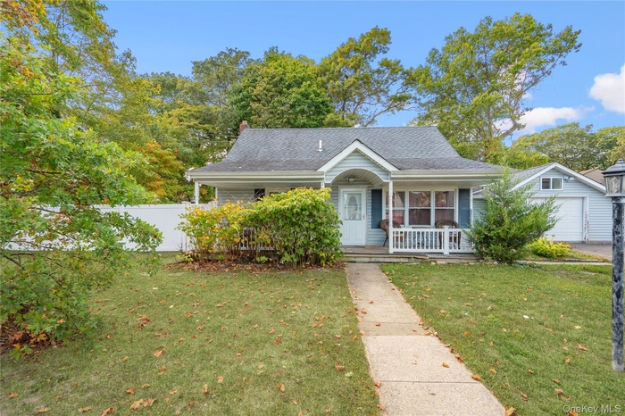 View of front of house with covered porch, a garage, roof with shingles, and a chimney
