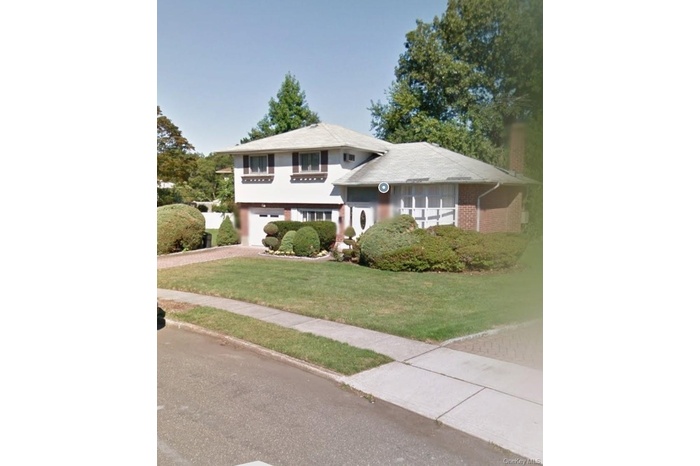 Split level home with driveway, a front lawn, and an attached garage